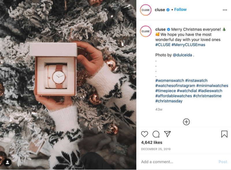 „@cluse“ „Instagram“ įrašas, kuriame pavaizduotas snaigėmis megztinio modelio, laikančio laikrodį priešais snieguotą medį, paveikslėlis, kurį sukūrė @dulceida su grotažymėmis #cluse ir #meryclusemas