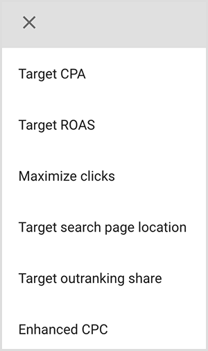 Tai „Google Ads“ taikymo parinkčių meniu ekrano kopija. Galimos parinktys yra tikslinis MUĮ, tikslinė SIG, maksimalus paspaudimų skaičiaus padidinimas, tikslinė paieškos puslapio vieta, tikslinio aukštesnio reitingo dalis, patobulintas MUP. Mike'as Rhodesas teigia, kad „Google Ads“ protingos taikymo parinktys naudoja dirbtinį intelektą, kad surastų žmones, turinčius reikiamą jūsų skelbimo tikslą.